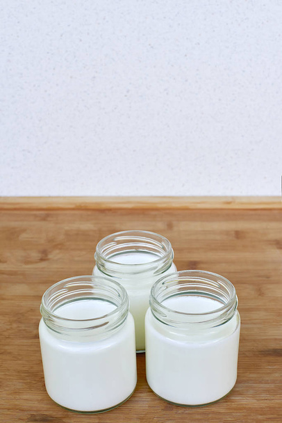 Tre barattoli di vetro con yogurt su fondo di legno
 - Foto, immagini