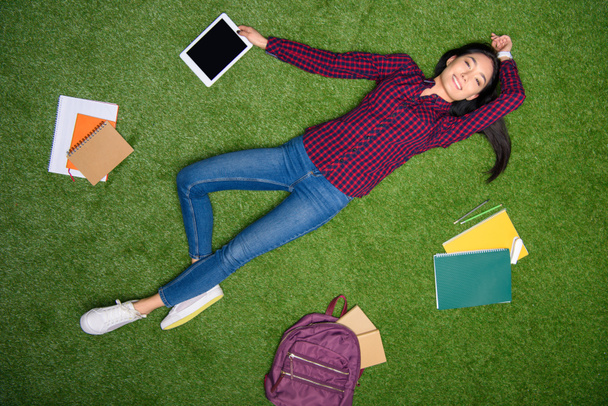 overhead view of smiling asian student lying on green grass - 写真・画像