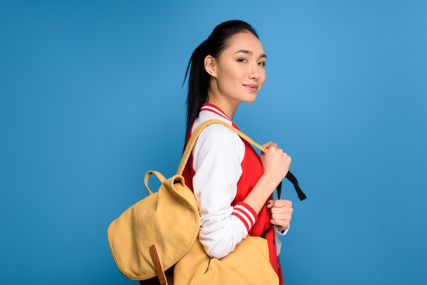 vista lateral de estudante asiático bonito com mochila isolada em azul
 - Foto, Imagem