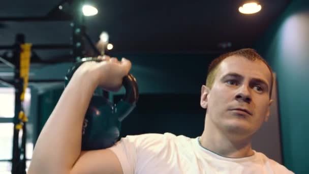 Γυμναστήριο άνδρας κάνει μια κατάρτιση βάρους σηκώνοντας βαριά kettlebell. Yong αθλητής κάνει kettlebell κούνιες. Bodybuilder kettlebell ανύψωσης - Πλάνα, βίντεο