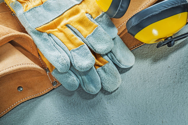 Set of leather tool belt protective gloves earmuffs on concrete  - Zdjęcie, obraz