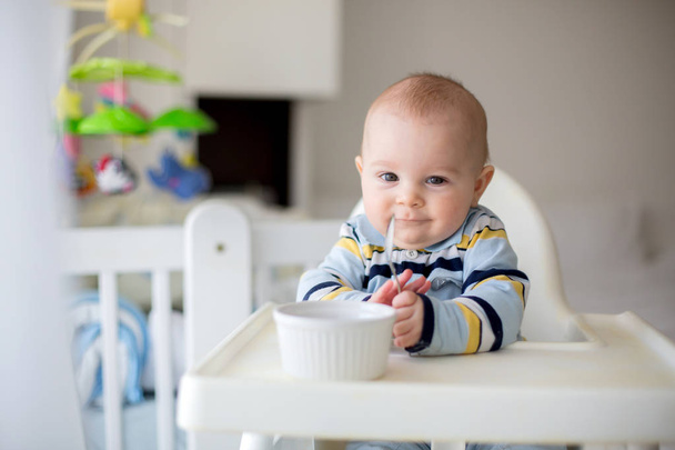 Cute little baby boy, eating mashed vegetables for lunch, mom fe - Fotó, kép