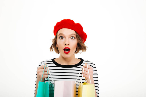 Shocked ginger woman holding packages and looking at the camera - 写真・画像