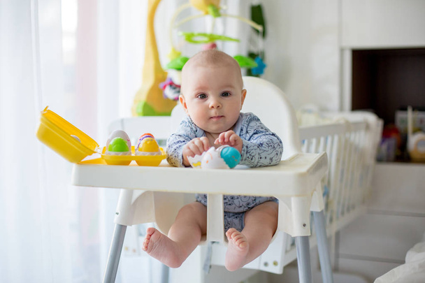 Cute little toddler boy, playing with plastic eggs, sitting in a - Foto, imagen