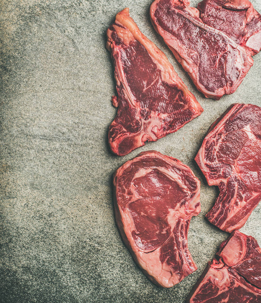 Fresh raw beef meat steak cuts over grey concrete background - Foto, Imagem