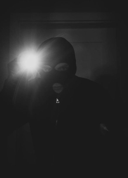 Dieb mit Maske und Taschenlampe im Haus. - Foto, Bild