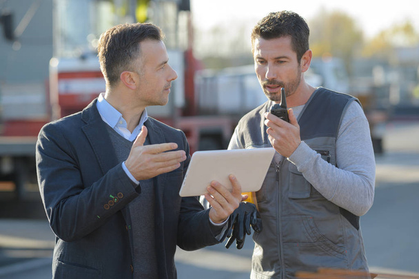 businessman with digital tablet talking to worker outdoors - Foto, Bild