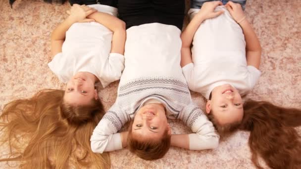Mladá maminka a její dvě dospívající dcery, ležící na podlaze doma - Záběry, video