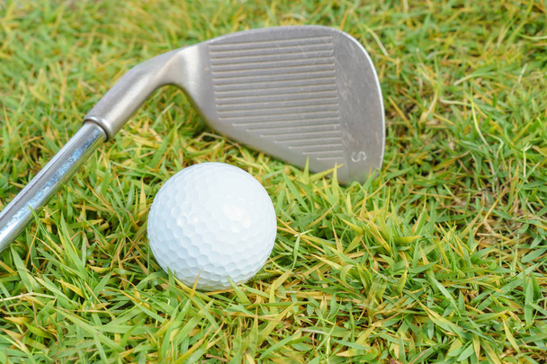 Golfclubs en de golfbal op groen gras achtergrond - Foto, afbeelding