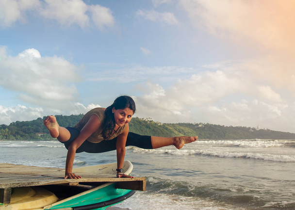 Uma menina no vestido colorido na praia está fazendo ioga, Galle, Sri Lanka
 - Foto, Imagem