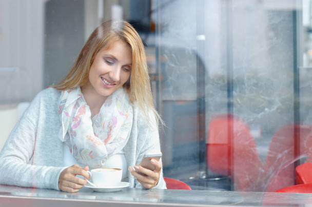 Mulher com sorriso bonito usar telefone celular enquanto descansa após o dia de trabalho no café
 - Foto, Imagem