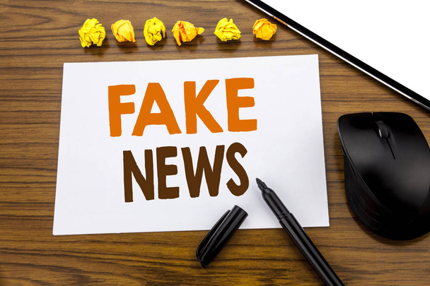 Conceptual hand writing text showing Fake News. Business concept for Hoax Journalism written on sticky note paper on the wooden background with marker mouse and tablet office view. - Photo, Image