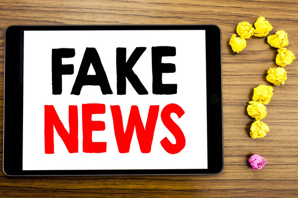 Writing text showing Fake News. Business concept for Hoax Journalism written on tablet computer on the wooden background with question mark made of folded paper. - Fotografie, Obrázek