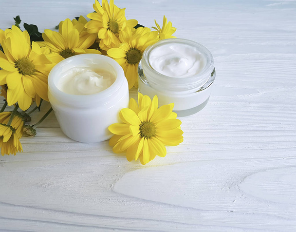 crema cosmetica in un vaso giallo crisantemo fiore di legno bianco
 - Foto, immagini