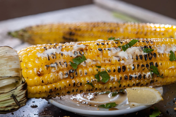 grilled corn on a wooden plate with lemon, herbs and spices - Fotoğraf, Görsel