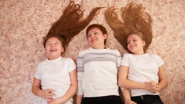 Portret młodej kobiety i dwóch nastolatków kobiece leżący na podłodze w domu, nogi na kanapie - Materiał filmowy, wideo