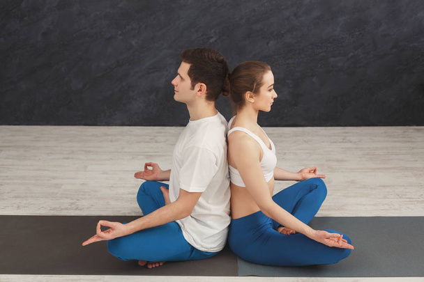 Young couple meditating together, back to back - Foto, imagen