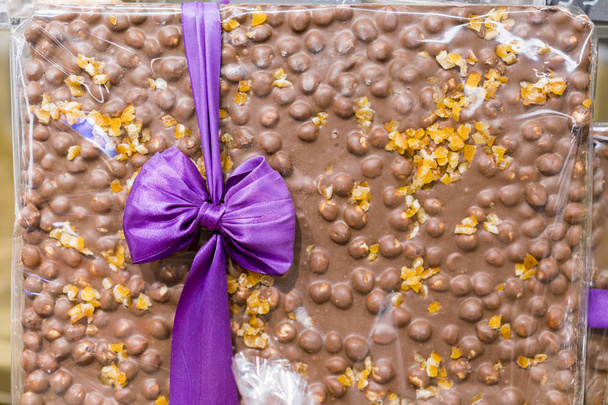 巨大なチョコレート ・ バーは、リボンと結ばれます。甘い贈り物です。ナッツとミルク チョコレート - 写真・画像