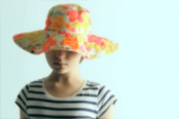 Zamazany obraz młoda dziewczyna ubrana kolorowy letni kapelusz i paski koszula, Zamknij się. Przycięte zaburzenia widzenia młodej dziewczyny. - Zdjęcie, obraz