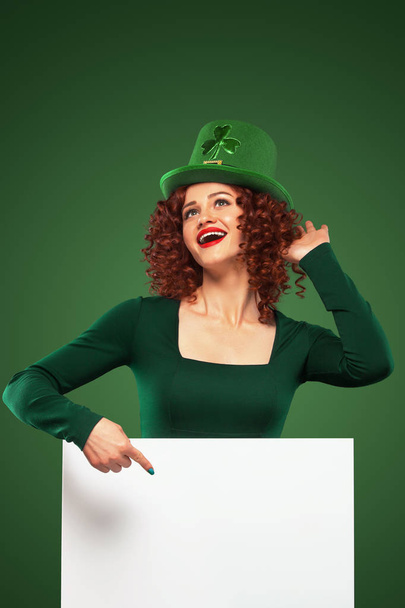 St Patrick Day. Young sexy oktoberfest woman, wearing a dress and green hat with white banner for copy space - Φωτογραφία, εικόνα