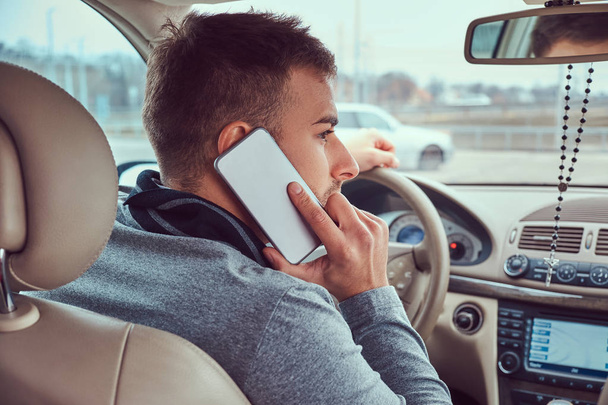 Portrait d'un bel homme d'affaires parlant au téléphone et conduisant sa voiture
. - Photo, image