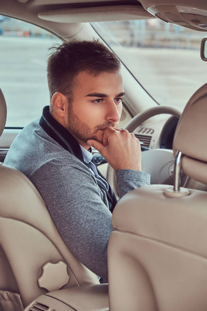Портрет красивого бизнесмена в сером свитере за рулем своей машины
. - Фото, изображение