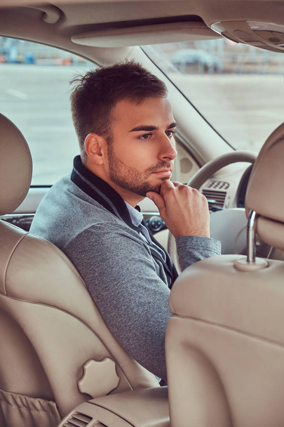Portrait of a handsome businessman in gray sweater driving his car. - Photo, Image
