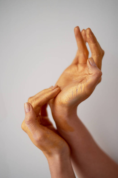Hands with long fingers in gold paint.Hand care - Foto, Imagen
