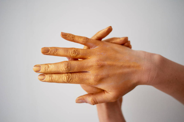 Hände mit langen Fingern in Goldfarbe. Handpflege - Foto, Bild