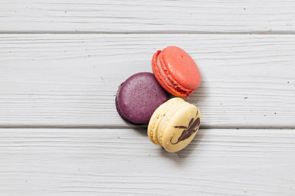 three delicious colorful macaroons on white wooden table, sweet dessert  - Foto, afbeelding