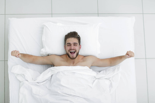Üstten Görünüm. mutlu adam rahat bir yatakta uyanma - Fotoğraf, Görsel