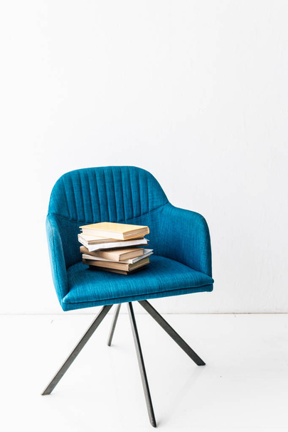 stack of different books on blue armchair  - Foto, imagen