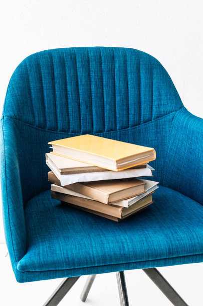 stack of different books on blue armchair  - Valokuva, kuva