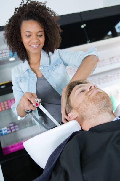 esteticista lavado clientes masculinos cabello en el salón
 - Foto, imagen