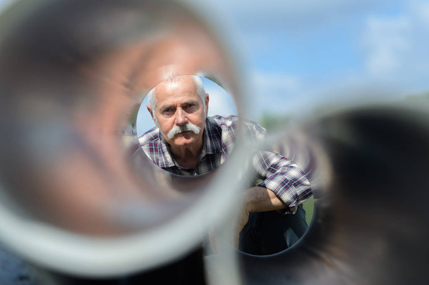 senior man looks through a metal tubes - Photo, image