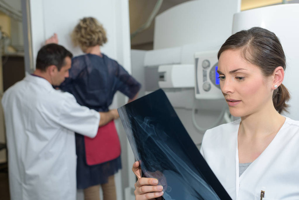 naispotilas seisoo röntgentutkimuksessa
 - Valokuva, kuva