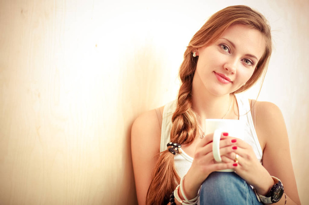 Beautiful woman sitting on the floor and holding a cup. Beautiful woman - Foto, Imagem