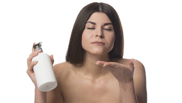Piękna Brunetka kobieta trzymając butelkę z balsam do ciała. Pojęcie piękna. na białym tle - Zdjęcie, obraz