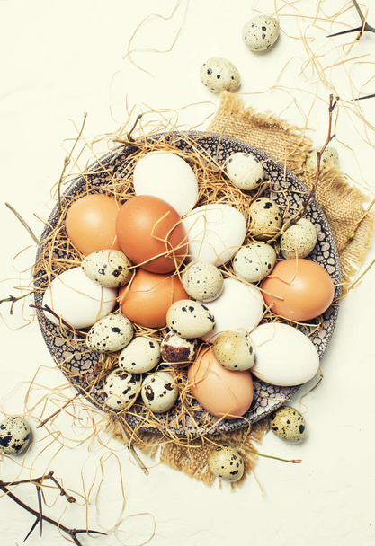 Multicolored chicken and quail eggs with straw and branches, spring Easter composition, top view - Foto, Imagem