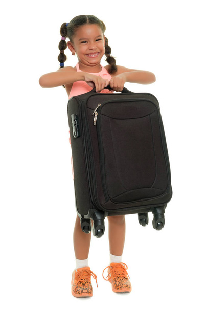 Small girl lifting a heavy  suitcase  - Isolated on white - Zdjęcie, obraz