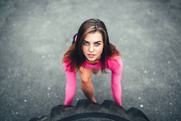 Genç sportif kız egzersiz ile büyük lastik açık - Fotoğraf, Görsel