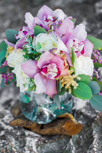 Τρυφερό νυφική ανθοδέσμη με λευκά τριαντάφυλλα σε γυάλινο δοχείο και ροζ ορχιδέες - Φωτογραφία, εικόνα