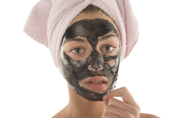 Black facial mask. Beautiful girl piling off black mask. Beauty concept - Valokuva, kuva