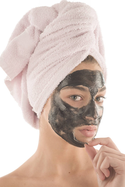 Black facial mask. Beautiful girl piling off black mask. Beauty concept - Foto, Bild