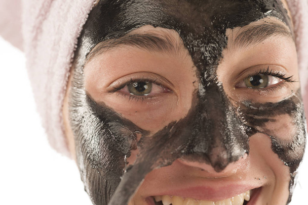 Black facial mask. Beautiful girl piling off black mask. Beauty concept - Foto, imagen