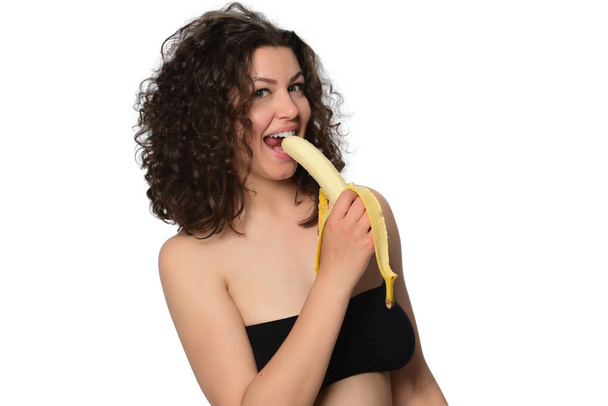 Kaunis nuori nainen syö banaania. eristetty valkoisella pohjalla
 - Valokuva, kuva