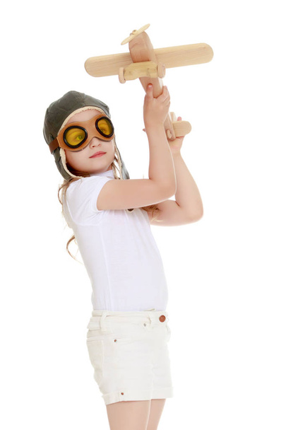 Маленькая девочка с деревянным самолетом в руке. - Фото, изображение