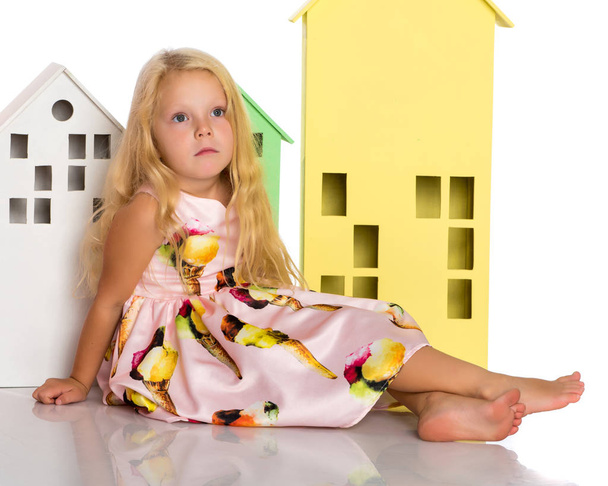 Little girl is playing with wooden houses. - Foto, imagen