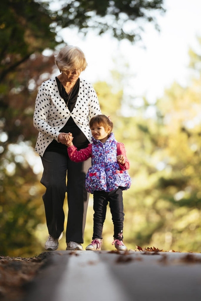 Abuela y nieta caminando por el sendero en el parque
 - Foto, Imagen