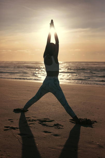 Silueta de joven deportista practicando yoga en la playa, concepto de vida sana y equilibrio natural entre el cuerpo y el desarrollo mental
 - Foto, imagen